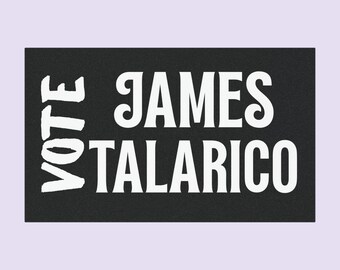 May include: A black rectangular doormat with the words "VOTE JAMES TALARICO" in white, bold, uppercase letters. The text is centered on the mat. The doormat is likely made of a durable material.