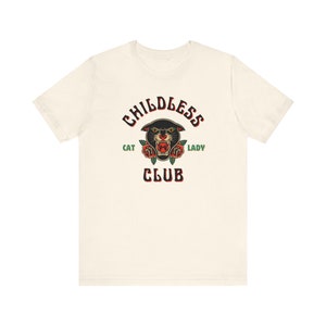 May include: A white t-shirt with a black panther head graphic and the text "Childless Cat Lady Club" in black and green.