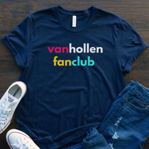May include: A navy blue t-shirt with the text "vanhollen fanclub" in colorful letters. The letters are pink, white, yellow, and blue.