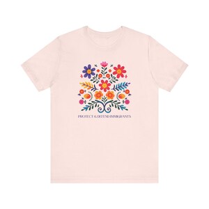 Camiseta "Proteger y defender a los inmigrantes": colorida camiseta de arte popular mexicano con flores. Nadie es ilegal en tierras robadas. Los inmigrantes hacen que Estados Unidos sea grandioso. Soft Pink
