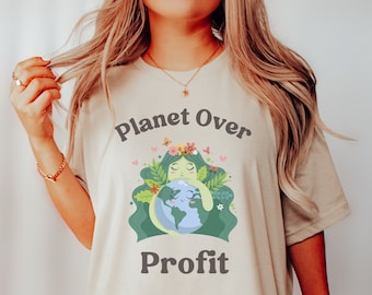May include: A beige t-shirt with a graphic of a woman hugging the Earth. The text "Planet Over Profit" is printed on the shirt.