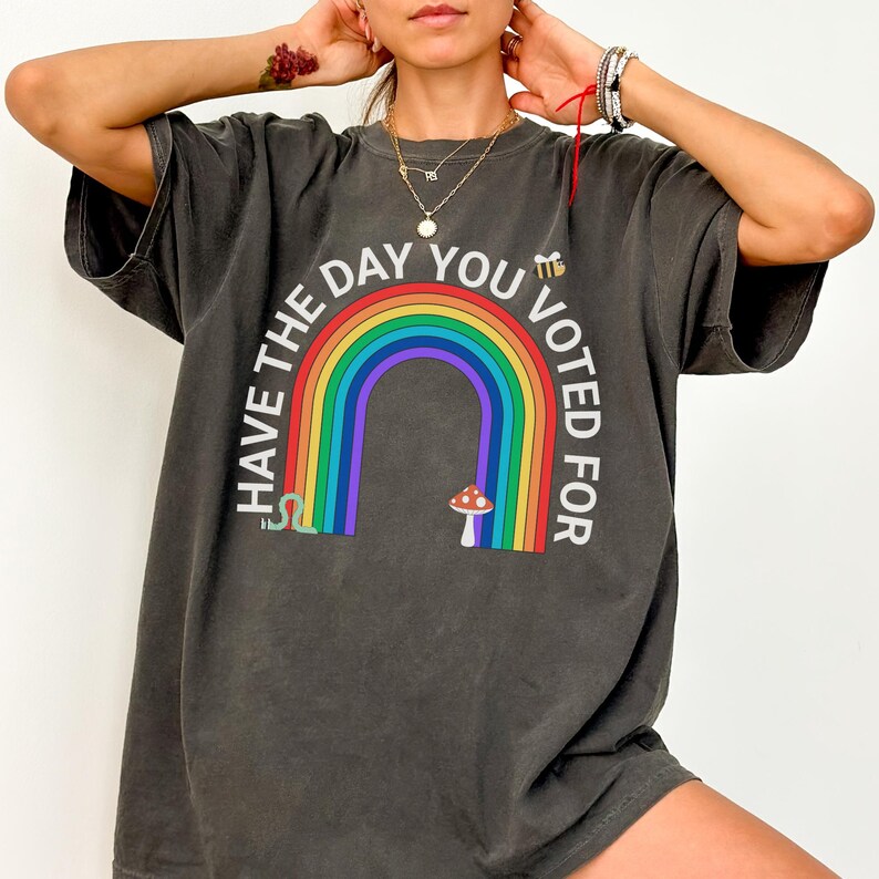 May include: A dark gray oversized t-shirt with a rainbow, a mushroom, a snake, and the text "Have the day you voted for".