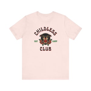 May include: A pink t-shirt with a black panther head graphic and the text "Childless Cat Lady Club" in black and green.