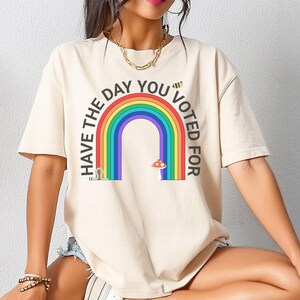 May include: A cream colored t-shirt with a rainbow graphic and the text "Have the day you voted for".