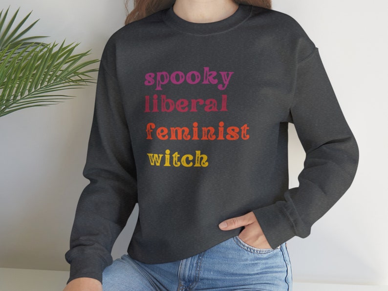 May include: A dark gray sweatshirt with the text "spooky liberal feminist witch" printed in rainbow colors.