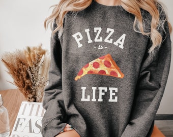 Könnte beinhalten: Ein grauer Pullover mit dem Aufdruck "Pizza is Life" auf der Vorderseite. Der Text ist weiß und es gibt eine Grafik einer Pizzastückes mit Pepperoni und Käse.