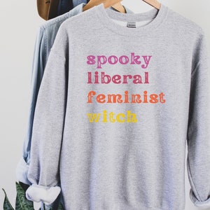 May include: Gray sweatshirt with the text "spooky liberal feminist witch" in rainbow colors.