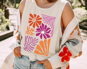 Op de afbeelding: Een crèmekleurige mouwloze tanktop met een rechthoekige grafische print van gestileerde bloemen en bladeren in levendige tinten oranje, roze en paars. Het ontwerp bevat een grote oranje margriet, een paarse bloem en diverse bladvormen.