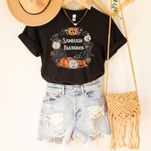 May include: Black t-shirt with a graphic of pumpkins, crows, and a clock with the text "Samhain Blessings".