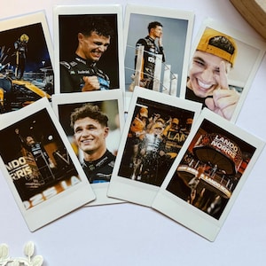 May include: A selection of polaroid-style photographs depicting Formula 1 racing moments. The images show drivers in various situations, including celebrations and action shots. The photos have a white border and are arranged on a light-coloured surface.