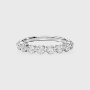 May include: A silver band ring featuring a series of round, clear gemstones. The gemstones are evenly spaced around the ring, creating a continuous line of sparkle. The ring is set against a plain, light background.