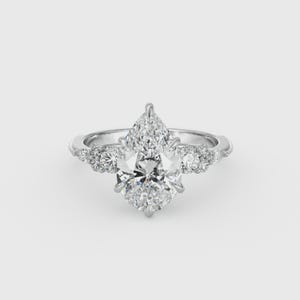 May include: A silver engagement ring with a large, pear-shaped diamond as the centerpiece. The ring features smaller diamonds on either side of the main stone and along the band, creating a sparkling, elegant design.