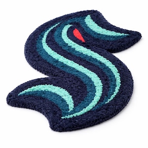 Peut inclure: Un tapis bleu marine en forme de "S" stylisé, orné de rayures ondulées dans des tons de bleu sarcelle, turquoise et marine, avec un petit accent rouge. Ce tapis décoratif convient à divers espaces. Le tapis est en matière pelucheuse.