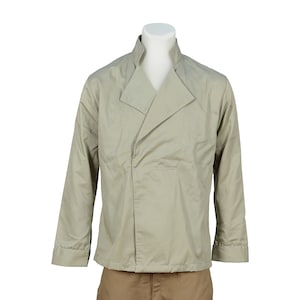 Puede incluir: Una camisa beige de manga larga con cuello mandarín y un pantalón marrón.