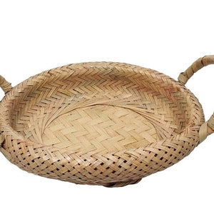 May include: A woven, light brown, oval-shaped basket with two handles. The basket is made of natural materials and has a woven pattern.
