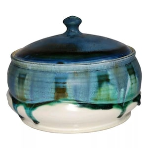 May include: A ceramic lidded jar with a blue, green, and white glaze. The jar has a rounded body and a domed lid with a knob.
