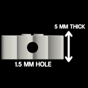 May include: A light gray rectangular component featuring a central circular opening and two small studs on the top surface. The object is labeled with text indicating it is 5 mm thick and has a 1.5 mm hole, providing clear technical specifications.