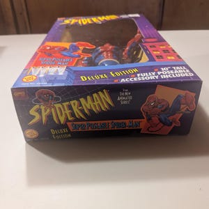 May include: A red and blue Spider-Man action figure in a box. The figure is 10 inches tall and fully poseable. The box features the text "Super Poseable Spider-Man" and "Deluxe Edition".