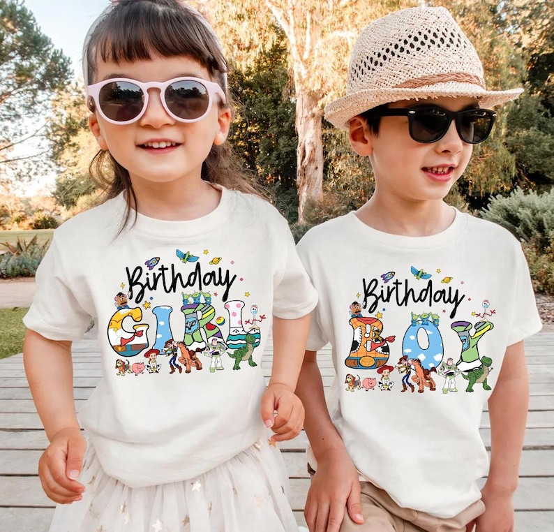 May include: Two children wearing white t-shirts with the text "Birthday Girl" and "Birthday Boy". The shirts feature colorful cartoon graphics and the word "Birthday" in script. The girl wears pink sunglasses, and the boy wears a straw hat and black sunglasses.