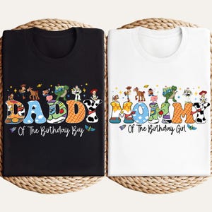 May include: Two t-shirts, one black and one white, with colorful text and cartoon character designs. The black shirt says "DADDY Of The Birthday Boy." The white shirt says "MOMMY Of The Birthday Girl."