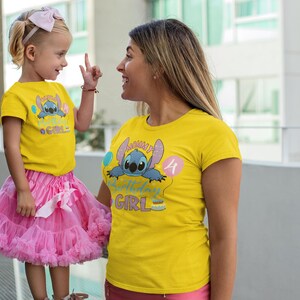 May include: Two people wearing matching yellow t-shirts with a cartoon character and the text "Birthday Girl". The child is wearing a pink tutu and a bow. The other person is wearing pink shorts.