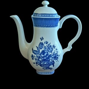 Pode incluir: Uma chaleira de cerâmica branca com um design floral azul e uma tampa. A chaleira tem um bico e uma alça.