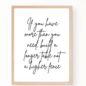May include: Black and white typography print with the quote "If you have more than you need, build a longer table not a higher fence". The print is framed in a light wood frame.