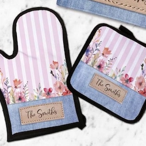 Puede incluir: Un guante de horno a rayas rosa y blancas con un diseño floral y un parche de mezclilla que dice "The Smiths". Un posavasos a juego a rayas rosa y blancas con un diseño floral y un parche de mezclilla que dice "The Smiths".