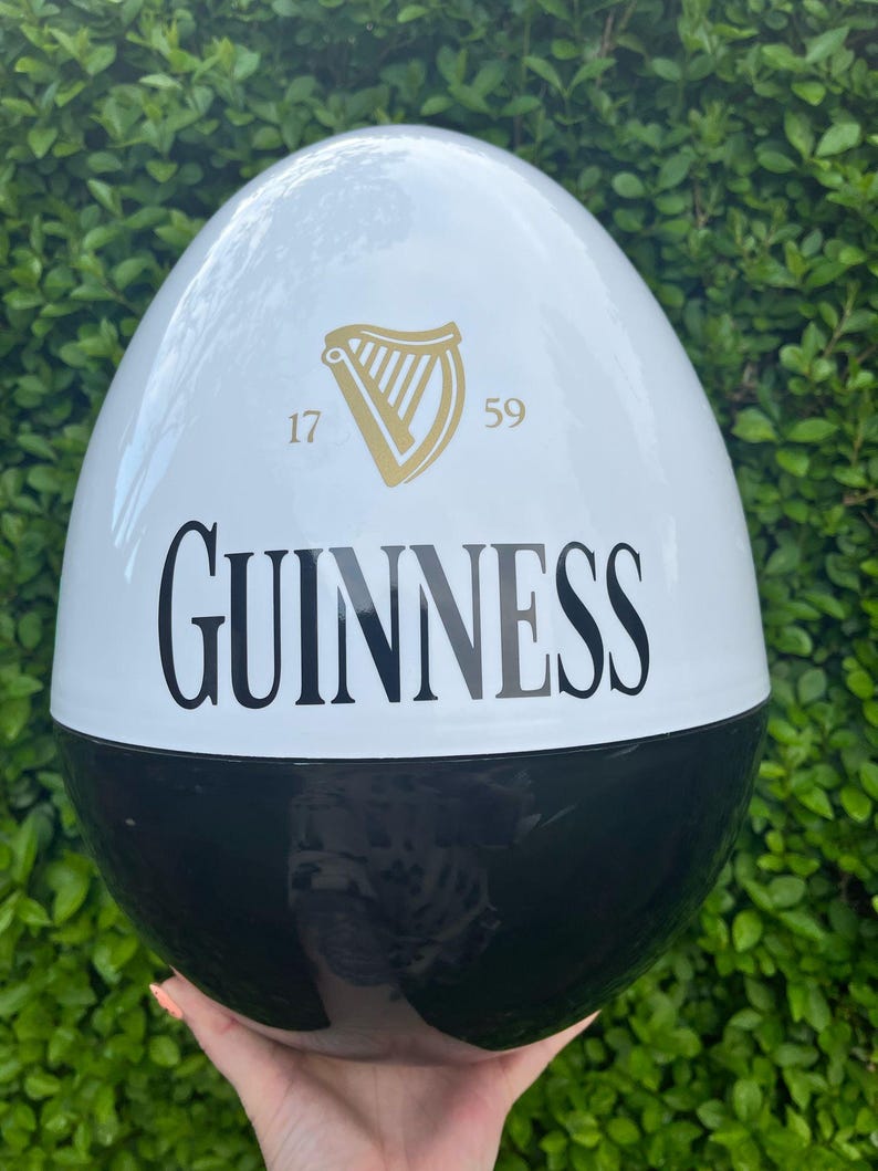 May include: A large, egg-shaped decorative item, split into black and white sections. The white section features the Guinness logo, a gold harp, and the numbers "17" and "59". The word "GUINNESS" is printed in large, black letters.
