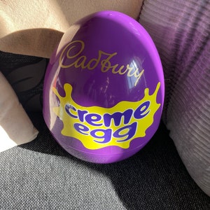 May include: A large purple plastic egg with the Cadbury logo and the words "creme egg" in yellow.