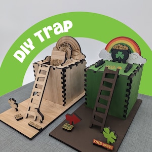 May include: Two wooden boxes with a trap door and a ladder. The boxes are decorated with a rainbow, clouds, a pot of gold, and a shamrock. The text "NOT A TRAP" is on the front of each box. The boxes are on a wooden base with the text "THIS WAY!" and "FAKE GOLD" on signs.