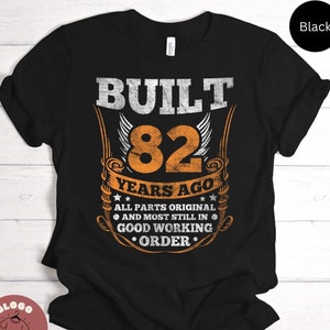 May include: Black t-shirt with orange text that reads "BUILT 82 YEARS AGO ALL PARTS ORIGINAL AND MOST STILL IN GOOD WORKING ORDER".