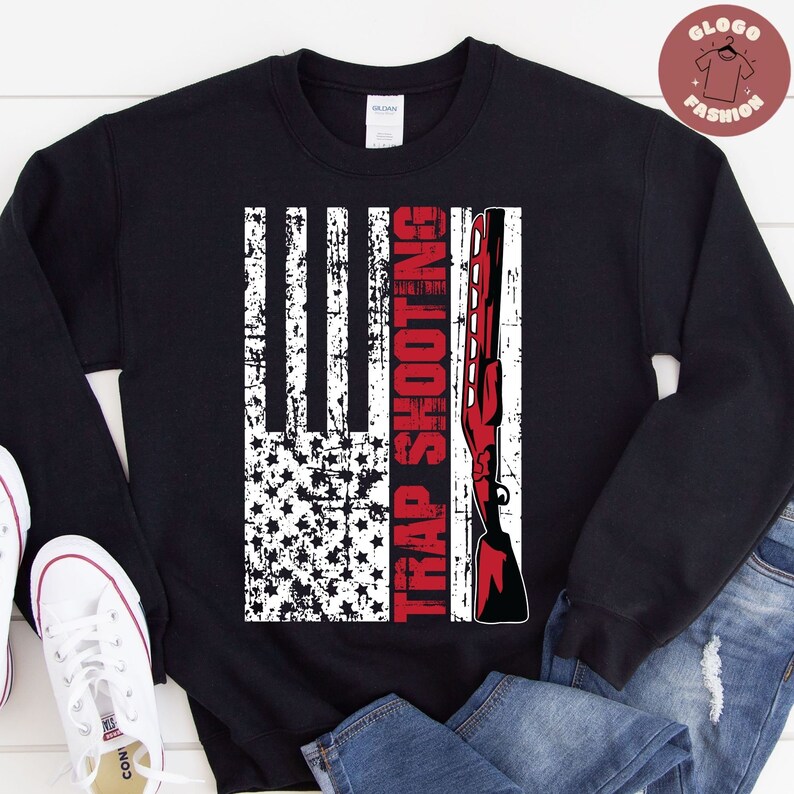 May include: Black sweatshirt with a distressed American flag design and the text "TRAP SHOOTING" in red.