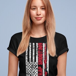 May include: Black t-shirt with a distressed American flag design and the text "Trap Shooting" in red.