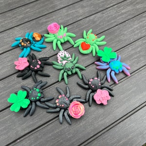 Puede incluir: Una colección de nueve figuritas de araña pintadas a mano y coloridas. Cada araña tiene un diseño único con flores, corazones y otros elementos decorativos. Las arañas están hechas de un material liso y brillante y son perfectas para agregar un toque caprichoso a cualquier decoración del hogar.