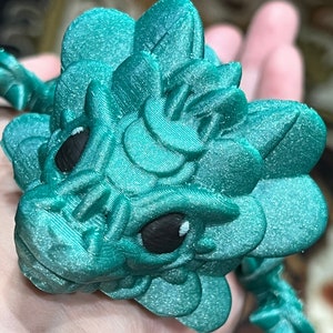 Op de afbeelding: Een 3D-geprint drakenbeeldje in teal groen met grote ogen en een textuur.