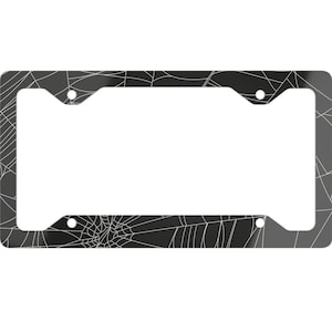 Könnte beinhalten: Schwarzer Kennzeichenrahmen mit weißem Spinnennetz-Design. Der rechteckige Rahmen hat abgerundete Ecken und vier Befestigungslöcher. Das Spinnennetz-Muster bedeckt die gesamte Oberfläche des Rahmens.