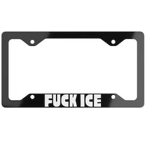 May include: Black license plate frame with the text "FUCK ICE" in white block letters. The frame has a rectangular shape with rounded corners and mounting holes.
