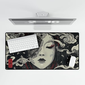 May include: A black rectangular desk mat featuring a stylized illustration of a woman's face with closed eyes, adorned with red accents and surrounded by swirling clouds. A white keyboard and mouse are on the mat, with a computer monitor above.