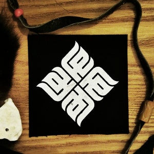 Pode incluir: Remendo de tecido preto com um design estilizado branco de quatro formas entrelaçadas. O design se assemelha a uma flor estilizada ou um padrão geométrico.