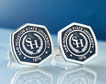 May include: A pair of silver cufflinks with a black and white enamel design. The design features a wreath with the letters "SH" in the center and the text "Sam Houston State University 1879".