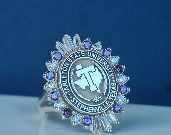 May include: A silver ring with a purple and white stone setting. The ring features the Tarleton State University logo, which includes the words "Tarleton State University", "Stephenville, Texas", and "1899".
