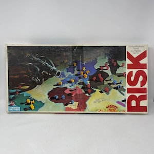 May include: Vintage Parker Brothers Risk board game. The game board depicts a world map with territories and continents. The box features a cannon illustration and the word "RISK" in large red letters. Includes game pieces.
