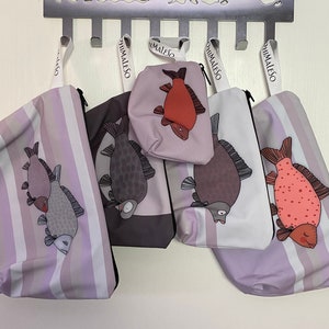Könnte beinhalten: Fünf lila und weiße gestreifte Reißverschlusstaschen mit verschiedenen Fischmotiven. Die Taschen haben den Schriftzug "Himaleso" aufgedruckt.