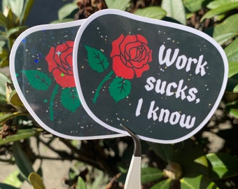 May include: Two black and white stickers with a red rose and the text "Work sucks, I know". The stickers are holographic and have a glittery finish.