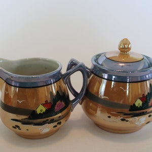 Sugar bowl and creamer set, orange lusterware, Made in Japan, with swan and cottage in trees