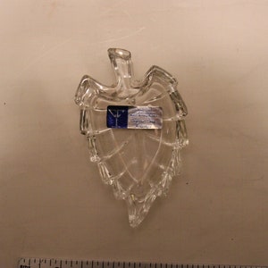 May include: A clear glass leaf-shaped dish with a blue and white label that reads "Y.I. Crystal, Made in China".