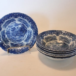 May include: Set of four blue and white ceramic bowls with a cottage scene design. The bowls have a scalloped edge and a floral pattern.