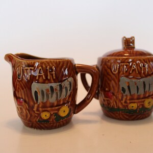 Thrifco sugar bowl (with lid) and creamer, souvenir of Utah, with embossed wagon