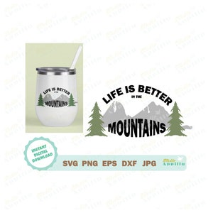May include: A white tumbler with a black and white design that says "Life is better in the mountains". The design includes a mountain range and two pine trees. The tumbler is on a white background.